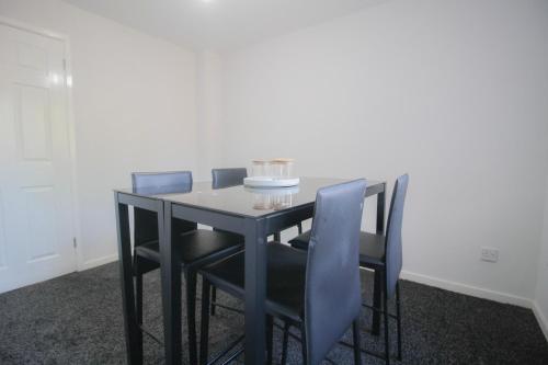 a black dining room table with blue chairs at Budget Modern Room in Bilston-Ideal for Work Trips in Coseley