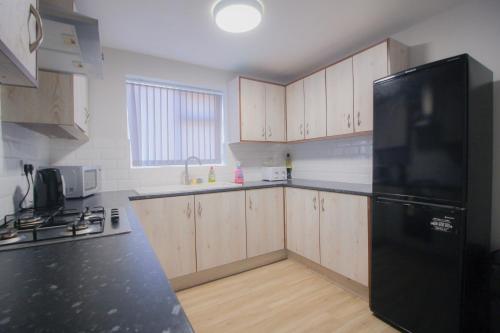 a kitchen with wooden cabinets and a black refrigerator at Budget Modern Room in Bilston-Ideal for Work Trips in Coseley