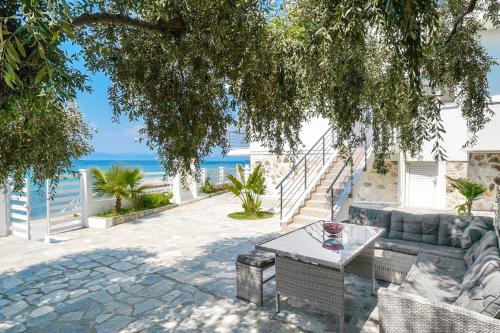 a patio with a couch and a table and the ocean at Chrissi Seastar in Skala Sotiros
