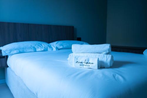 a white bed with blue pillows and a sign on it at MIA HOME experience in Milan