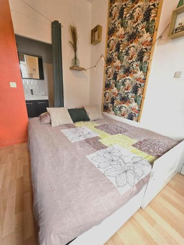 - un grand lit dans une chambre avec un mur dans l'établissement Le studio Naturel, à Hénin-Beaumont