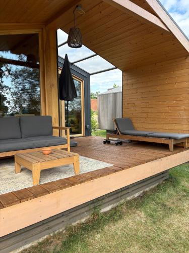 a wooden deck with a couch and chairs on it at 108 - Tiny House mit Blick ins Grüne in Bleckede