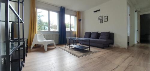 a living room with a couch and a table at Appartement calme 3 chambres avec lit double Wifi - Parking facile in Vandoeuvre-lès-Nancy