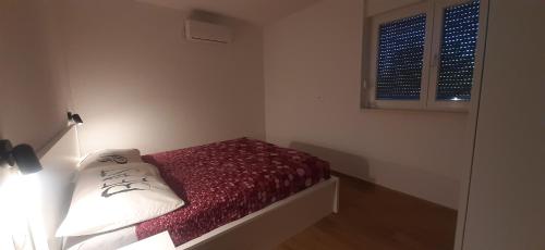 a small bedroom with a bed with red sheets and white pillows at Good vibes in Rogoznica