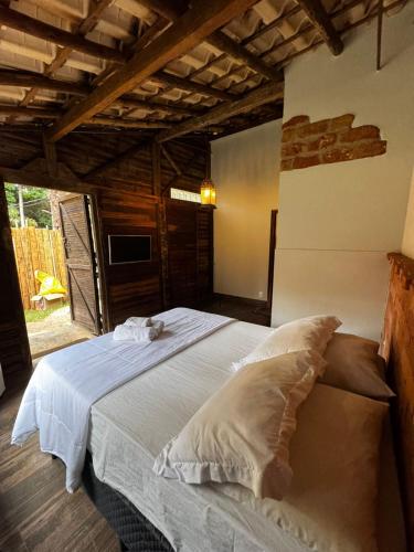 a bedroom with a large white bed in a room at Cantinhos da Mata Suítes Rústicas de Luxo Serra do Cipó MG in Serra do Cipo