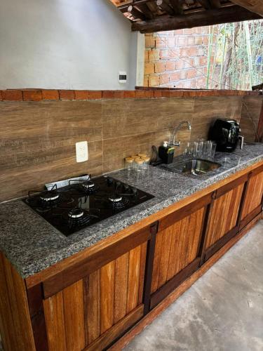 a kitchen counter with a stove and a sink at Cantinhos da Mata Suítes Rústicas de Luxo Serra do Cipó MG in Serra do Cipo