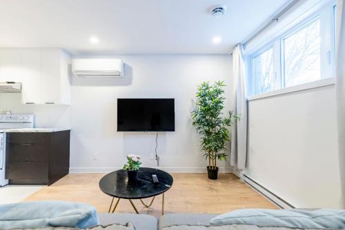 a living room with a table and a tv on a wall at Longueuil New Stylish 3-BDR free parking close to Dix 30&DT in Longueuil