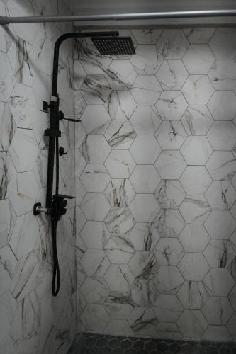 a bathroom with a white tiled wall with a shower at Casa Zelaya Hillside Retreat in Utila