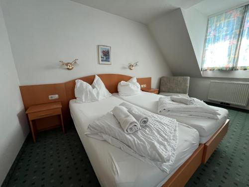 a bedroom with two beds with white sheets and towels at Aparthotel Mariazellerhof in Sankt Pölten
