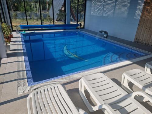 a swimming pool with two chairs and a boat in it at Cabanuțele din Lemn in Chişcău