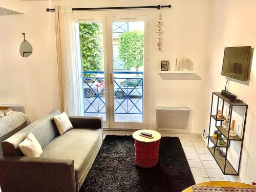 een woonkamer met een bank en een raam bij La Cabane de Riva Bella in Ouistreham