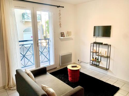 een woonkamer met een bank en een televisie bij La Cabane de Riva Bella in Ouistreham