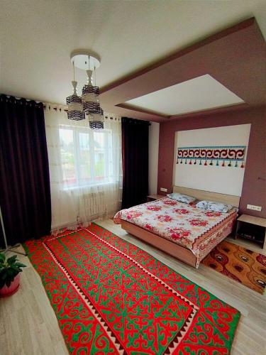 a bedroom with a bed and a rug on the floor at Guest House Nur in Kochkor