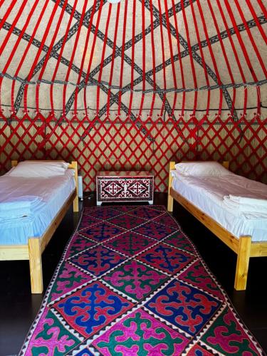 a room with two beds and a rug in a yurt at BarBulak Yurt Lodge in Bar-Bulak