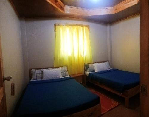 two beds in a small room with a window at Mother Mary Inn in Sagada