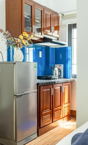 a kitchen with a stainless steel refrigerator and wooden cabinets at Close to My Khe Beach I Food street I Sóng Homestay in Da Nang