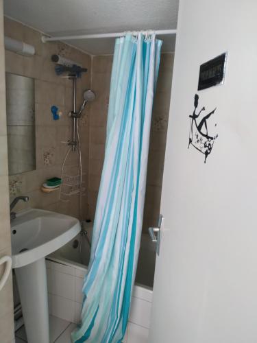 une salle de bain avec un rideau de douche bleu à côté d'un lavabo dans l'établissement Front de Mer, à Saint-Mandrier-sur-Mer
