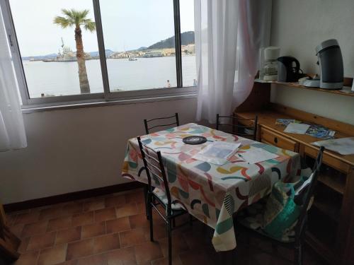 une table et des chaises dans une pièce avec une fenêtre dans l'établissement Front de Mer, à Saint-Mandrier-sur-Mer