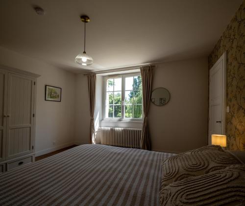 a bedroom with a bed and a window at Domaine de Pourrouquet - Demeure de charme et Gîte in Vic-Fezensac