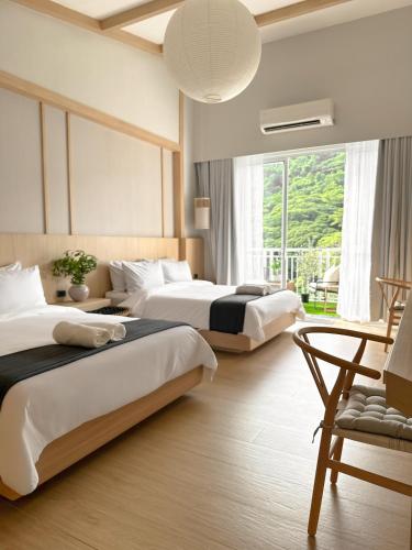 a hotel room with two beds and a window at Yugen Suites at Pico De Loro in Nasugbu