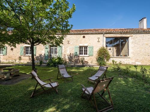 a group of chairs sitting in the grass in front of a building at Domaine de Pourrouquet - Demeure de charme et Gîte in Vic-Fezensac