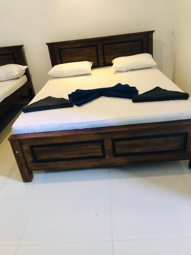 a bed with a wooden frame and white sheets at Truly Hostel Kandy in Kandy