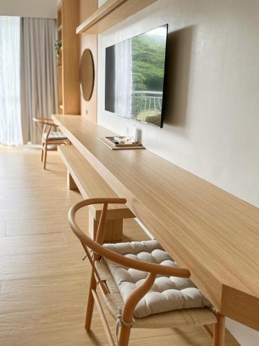 a room with a long wooden table with a television on the wall at Yugen Suites at Pico De Loro in Nasugbu