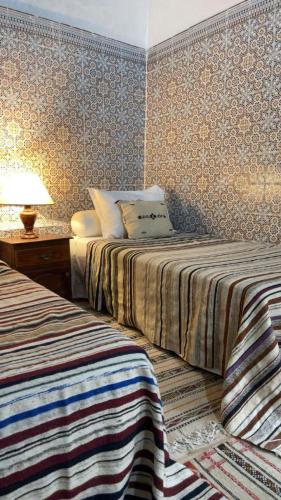 a bedroom with two beds and a table with a lamp at Riad Diafa in Oulad Akkou