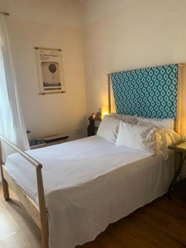 a bedroom with a large white bed with a blue headboard at La Meridiana in Vicopisano