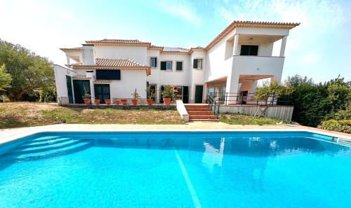 a large swimming pool in front of a house at Family Villa with Pool & Huge Garden - Arrábida Trails & Beaches Nearby in Setúbal