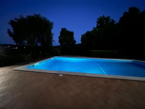 a blue swimming pool at night at Family Villa with Pool & Huge Garden - Arrábida Trails & Beaches Nearby in Setúbal