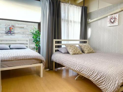 - une chambre avec 2 lits et une fenêtre dans l'établissement C涉谷区域徒步到达西新宿五丁目8分钟乘地铁到达新宿4分钟最多5人c, à Tokyo