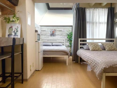 une petite chambre avec deux lits et une fenêtre dans l'établissement C涉谷区域徒步到达西新宿五丁目8分钟乘地铁到达新宿4分钟最多5人c, à Tokyo