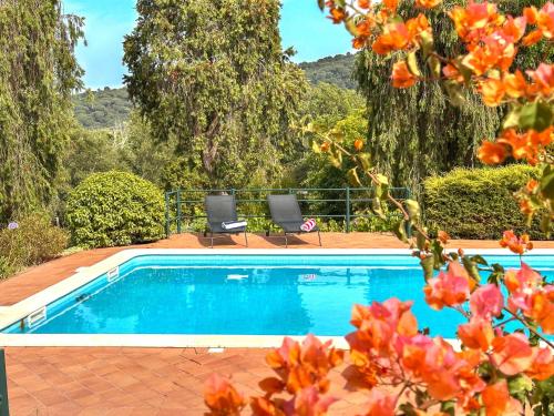 a swimming pool with two chairs and flowers at Family Villa with Pool & Huge Garden - Arrábida Trails & Beaches Nearby in Setúbal