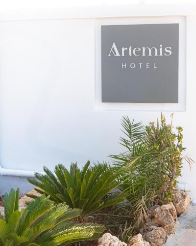 a sign for an athens hotel on a wall with plants at Artemis in Makry Gialos