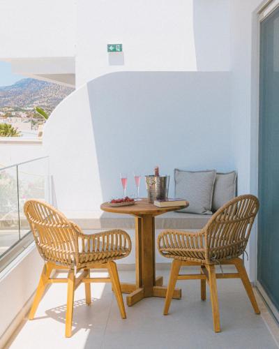 a table and two chairs on a balcony with glasses at Artemis in Makry Gialos