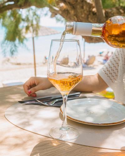 a person pouring wine into a wine glass on a table at Artemis in Makry Gialos