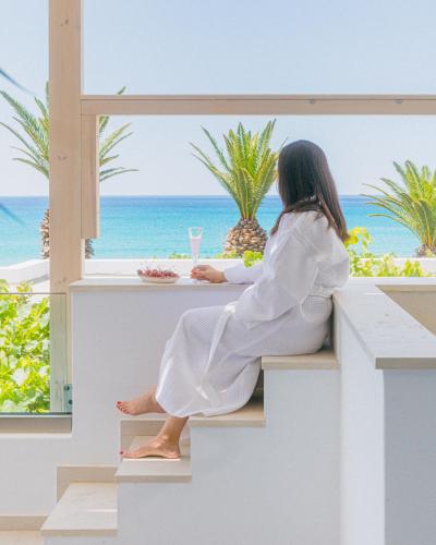 a woman sitting at a table looking out at the ocean at Artemis in Makry Gialos