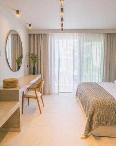 a bedroom with a bed and a desk and a mirror at Artemis in Makry Gialos