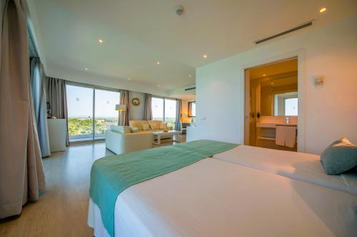 a bedroom with a large bed and a living room at Playa Esperanza Resort Affiliated by Meliá in Playa de Muro