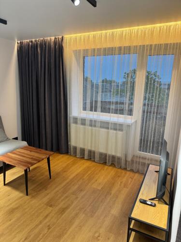 a living room with a table and a large window at Aleksandra Apartment in Ventspils
