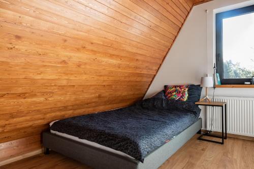a bed in a room with a wooden wall at Apartament przy Gazowników 12 in Brenna