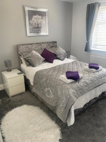 a bedroom with a bed with purple pillows on it at OneDouble room, one small double room, one en-suite studio room near to Wembley stadium in London