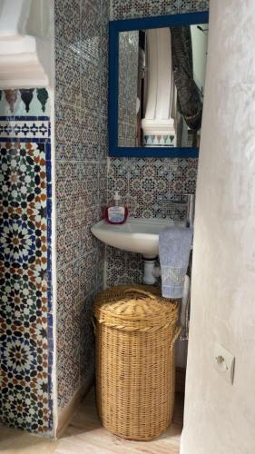 a bathroom with a sink and a mirror and a basket at Riad Diafa in Oulad Akkou