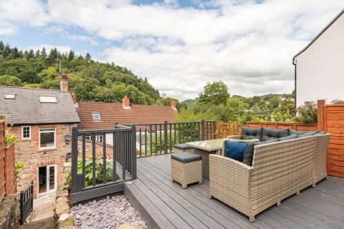 a balcony with a couch and a table on a deck at River Cottage - Idyllic & Chic Retreat, Wye Valley in Newland