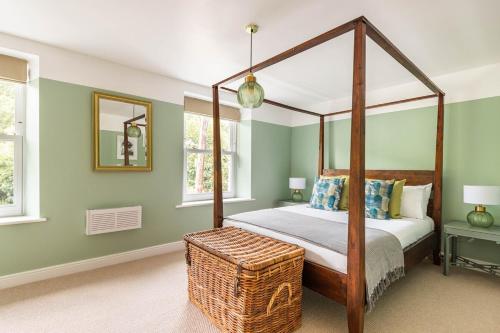 a bedroom with a canopy bed and a wicker basket at River Cottage - Idyllic & Chic Retreat, Wye Valley in Newland