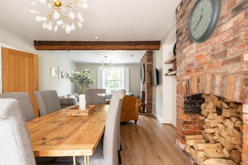 a dining room with a brick fireplace and a wooden table at River Cottage - Idyllic & Chic Retreat, Wye Valley in Newland
