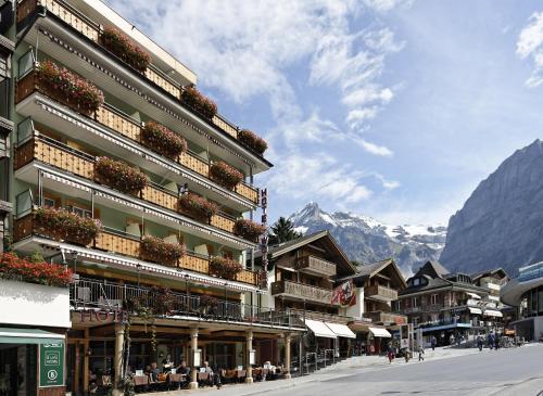 a building on a street with mountains in the background at Hotel Central Wolter - Grindelwald in Grindelwald
