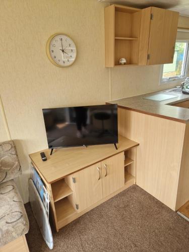 a kitchen with a tv and a clock on the wall at The Cosy Coastal Caravan in Morecambe