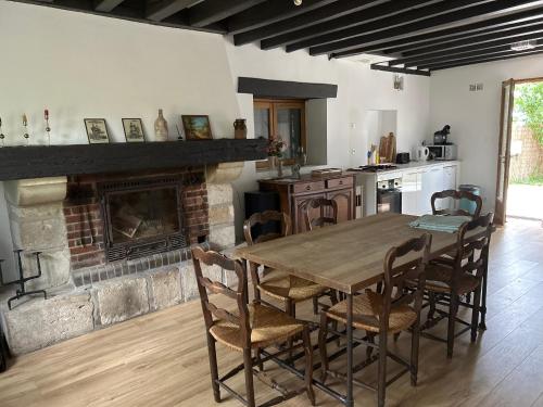 une cuisine avec une table en bois et une cheminée dans l'établissement Charmante maison de campagne, à Le Charme